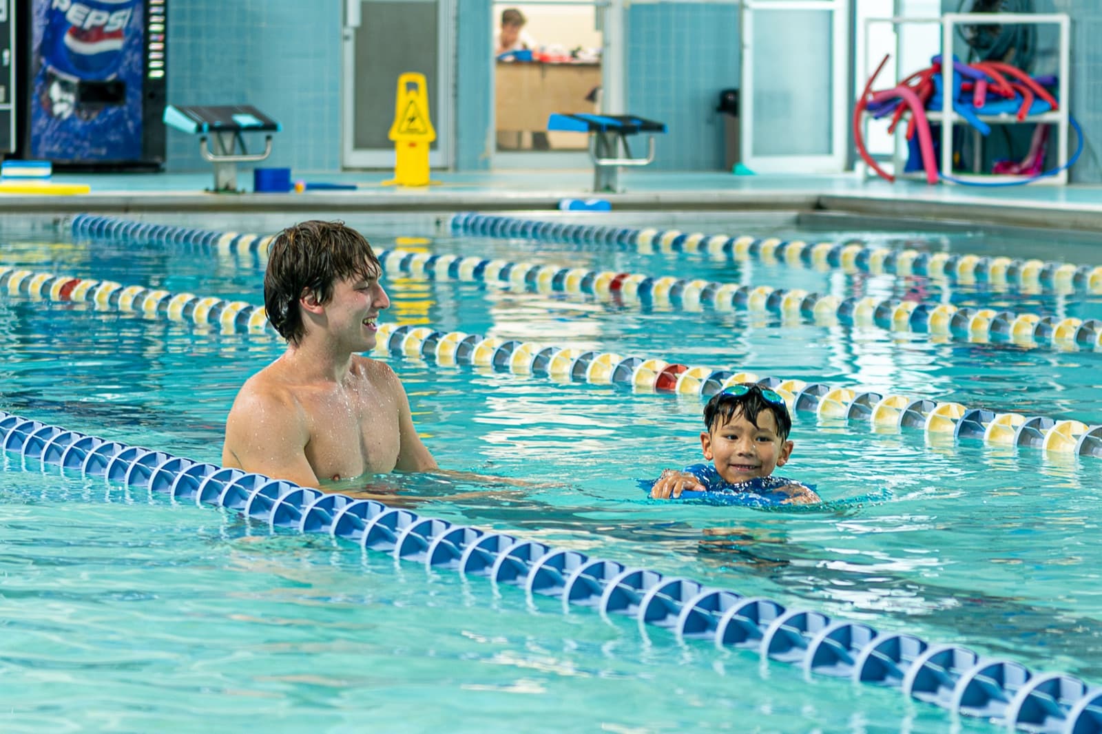 SafeStroke coach guiding a young swimmer through a back float