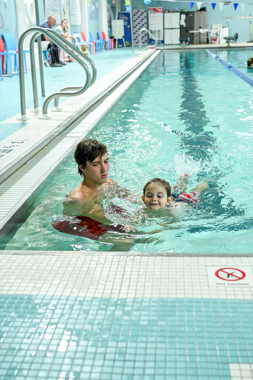 Young swimmer smiling with a kickboard during a SafeStroke lesson